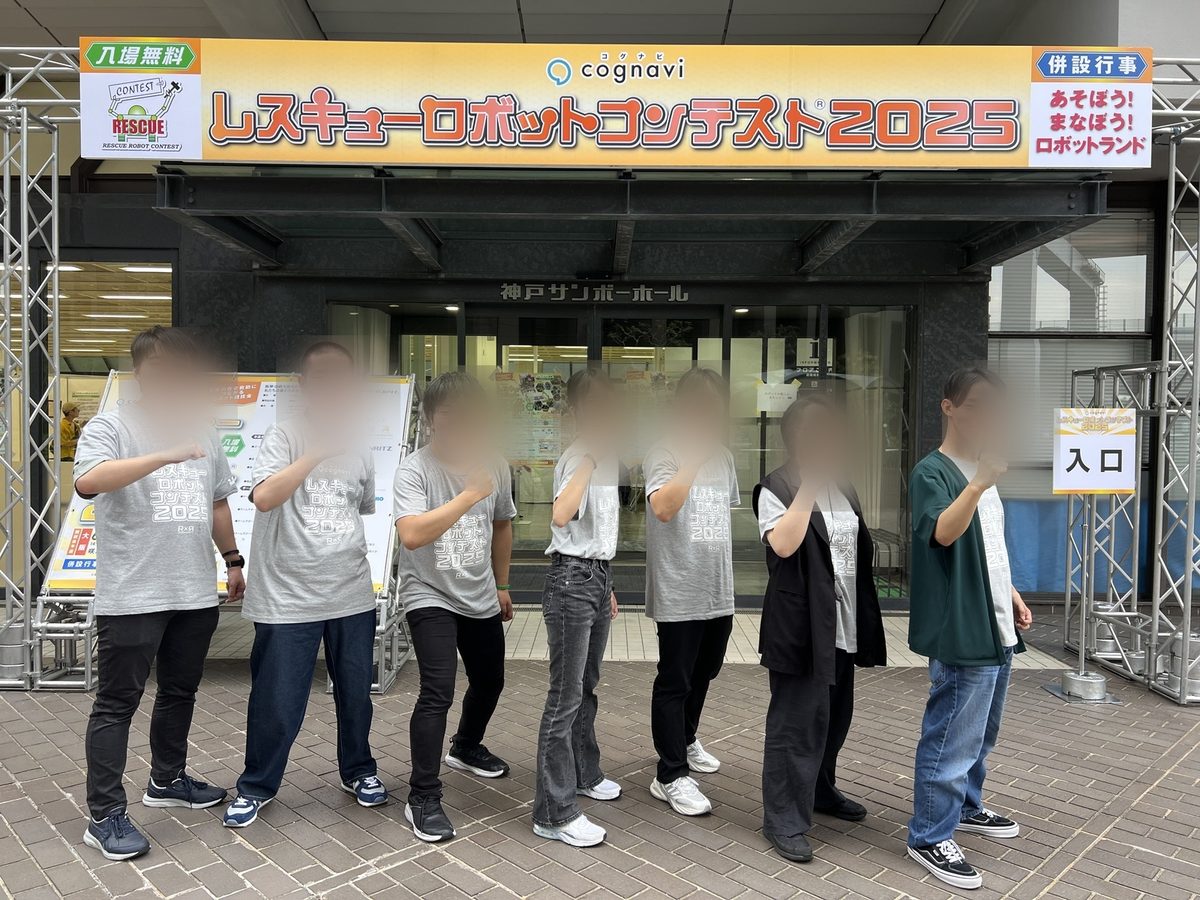 大会会場の前でポーズをとるチームメンバー